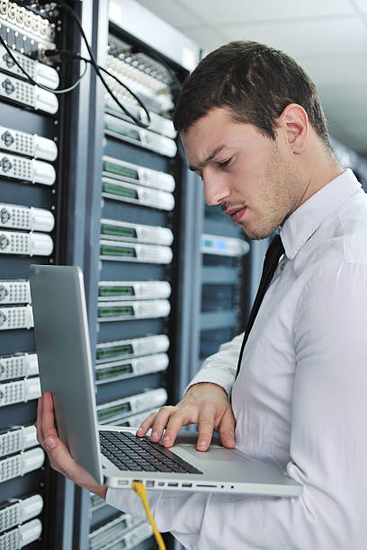 istock Young man working on laptop in a server room 142328475