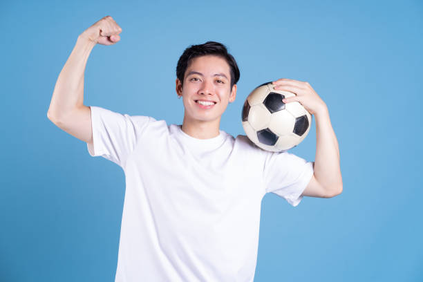 istock Young Asian man holding ball on background 1423285444