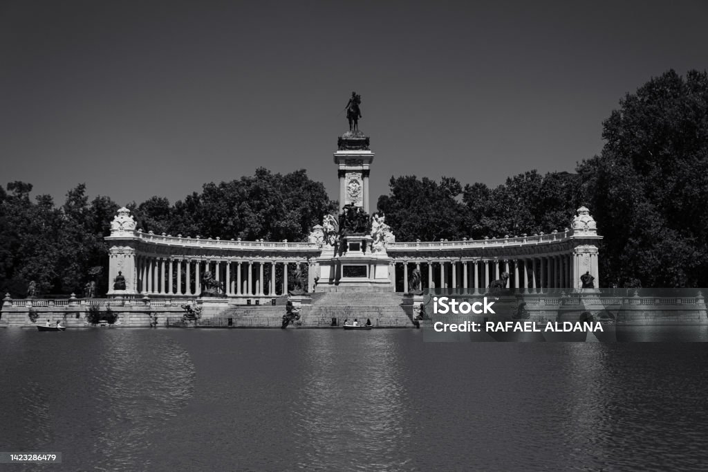 Large pond of El Retiro Pond in the most important park in the city of Madrid. In the background, a monument to King Alfonso XII. Architectural Column Stock Photo