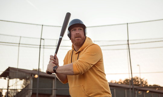 Overweight middle aged man on a diamond with a baseball bat
