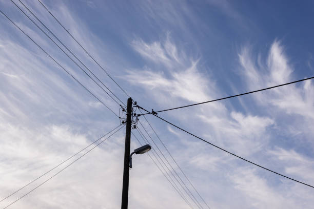 istock Wooden power pole against blue sky with clouds 1423288289