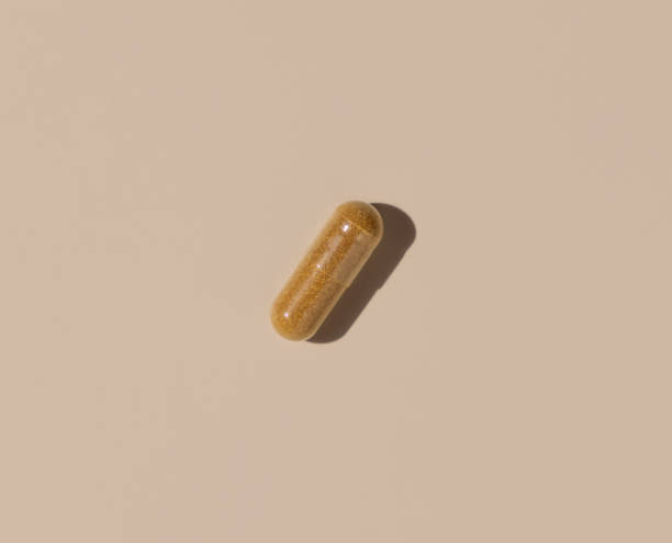 istock Brown Medical capsule on light beige top view, hard shadows. Taking dietary supplements 1423288568