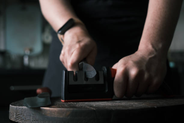 istock Woman is sharpening a kitchen knife using knife sharpener in domestic kitchen 1423292213