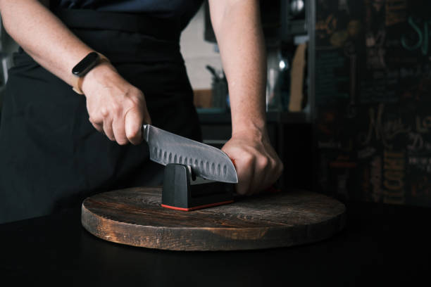 istock Woman is sharpening a kitchen knife using knife sharpener in domestic kitchen 1423292245
