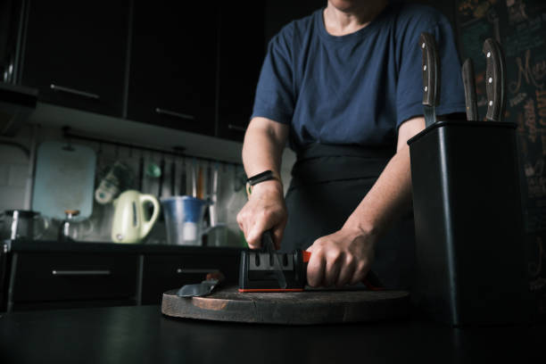 istock Woman is sharpening a kitchen knife using knife sharpener in domestic kitchen 1423292334