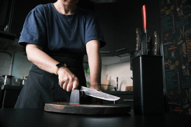 istock Woman is sharpening a kitchen knife using knife sharpener in domestic kitchen 1423292526