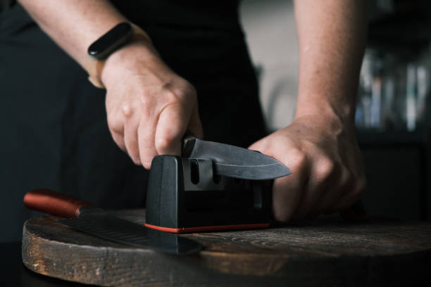 istock Woman is sharpening a kitchen knife using knife sharpener in domestic kitchen 1423292720