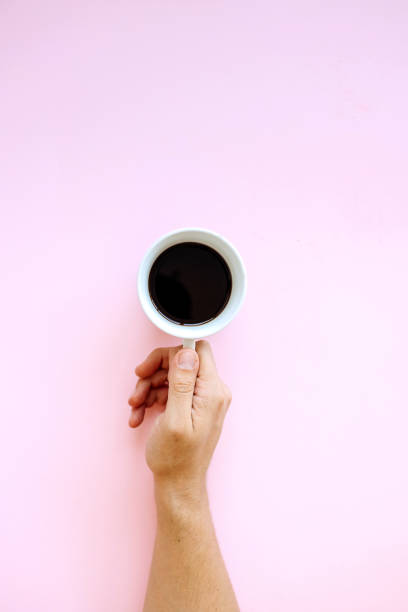 Male hand reaching for coffee on a pink background Male hand reaching for coffee on a pink background black coffee from above stock pictures, royalty-free photos & images
