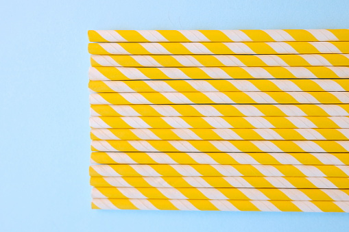 Yellow and white stripped drinking straws arranged on a blue background