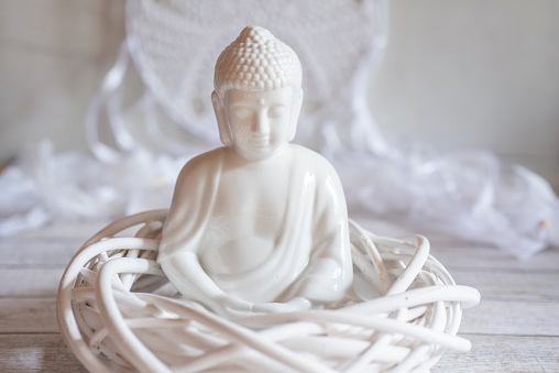 white Buddha figurine in white ambience with atmospheric lighting
