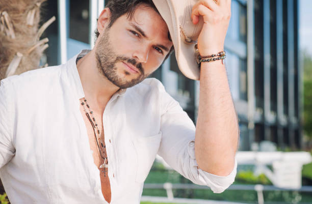 Man model dressed in hat, outdoor photo against city landscape