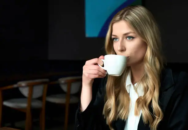 Photo of Atractive young woman drinking coffee in the morning at restaurant and thinking about new start-up project idea. Milenial lifestyle.