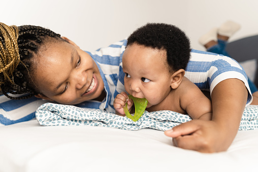 Portrait of a happy African American woman playing with her cute baby boy and enjoying motherhood at home