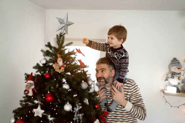 istock Father and his toddler son decorating a Christmas tree together 1423301664