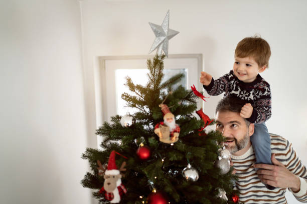 istock Father and his toddler son decorating a Christmas tree together 1423301669