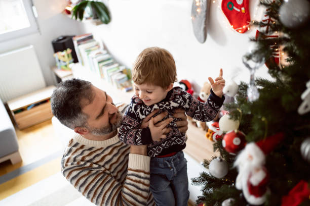 istock Father and his toddler son decorating a Christmas tree together 1423301717