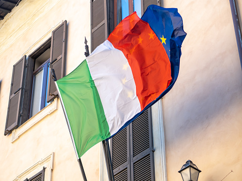 Two flags, Italian and European Union, are flying outside a building in Rome, Italy.