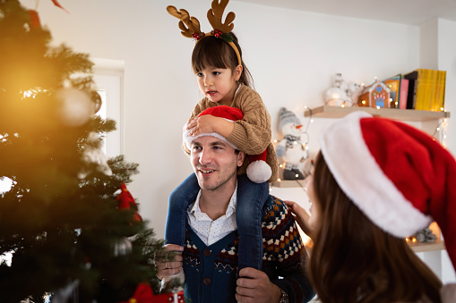 Cheerful multiracial parents with daughter decorating a Christmas tree