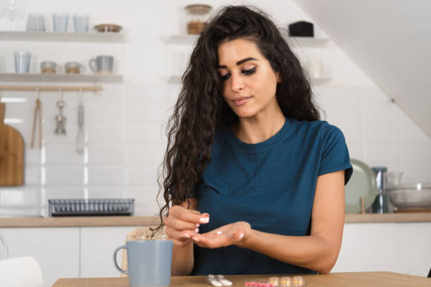 istock Woman sitting alone in her kitchen and taking her vitamins 1423304610