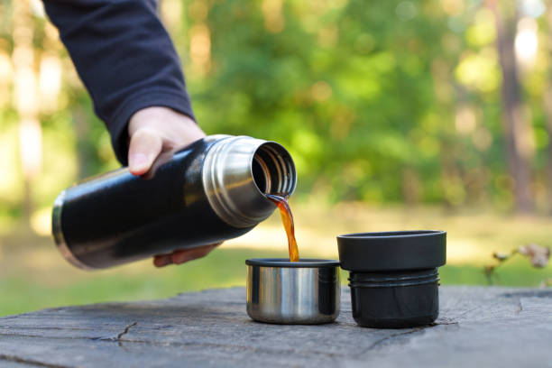 istock Man pouring coffee from thermos flask outdoors 1423306342