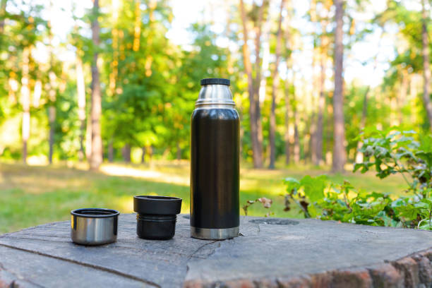 istock Black thermos bottle and cups on a tree stump 1423306373