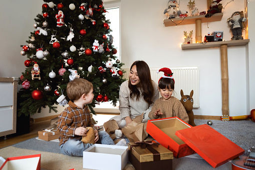 Multiracial family together opening their Christmas presents during Christmas morning