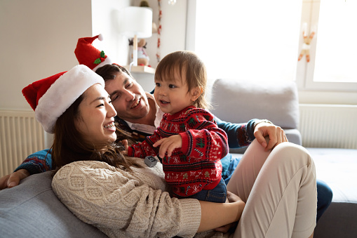 Multiracial parents playing with their toddler daughter during Christmas morning