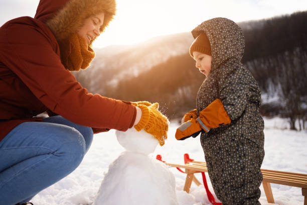 Caucasian mother and son, making a snowman