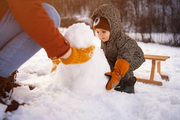 istock Caucasian mother and son, making a snowman 1423307392