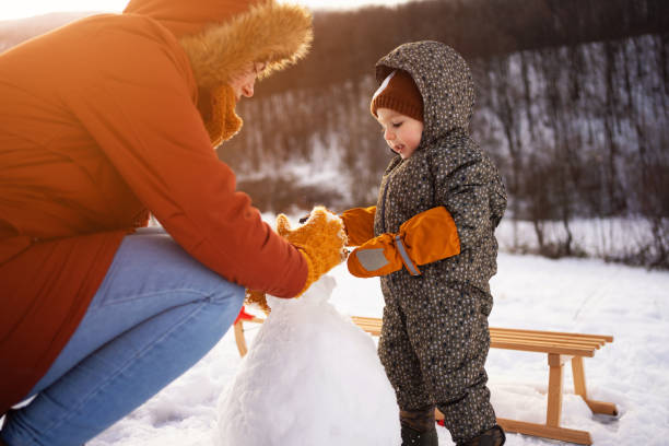 istock Caucasian mother and son, making a snowman 1423307428