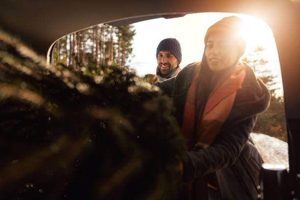 istock Couple packing Christmas tree into car trunk 1423309001
