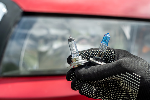 service man replacement halogen car bulb of the front headlight, repairing auto