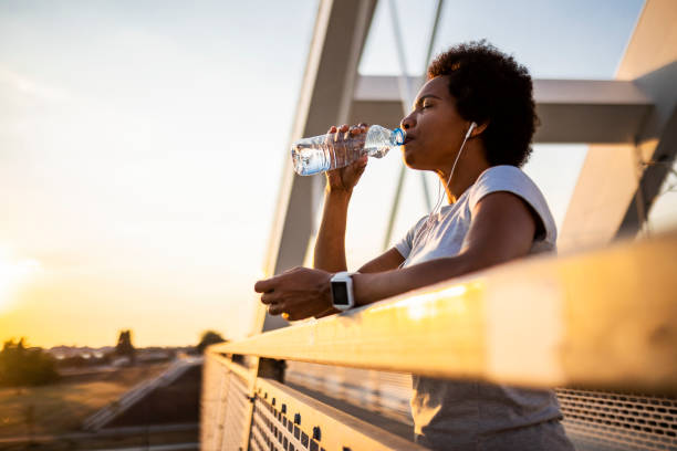 istock Young woman jogger taking a break drinking water 1423310476