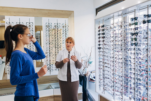 A professional optician advises a teenage girl to choose the appropriate glasses. She offers her glasses that are both beautiful and easy to wear