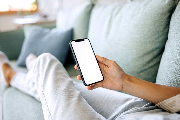 istock Closeup of woman using mobile phone with empty screen at home 1423312931