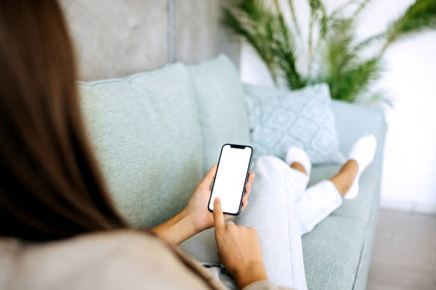 istock Woman using smart phone while relaxing on a sofa at her home 1423312932