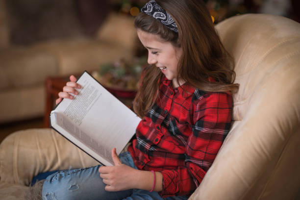 Girl laughing when reading a book stock photo