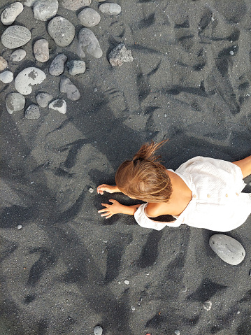 girl playing with volcanic sand in the beach of lanzarote