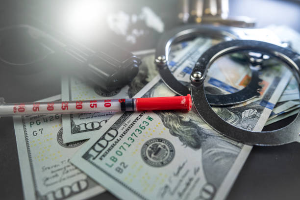 검은 테이블에 고립 된 소음기와 수갑이있는 마약과 돈 총. - narcotic gun medicine currency 뉴스 사진 이미지