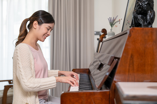 happy woman playing piano inside house on holiday