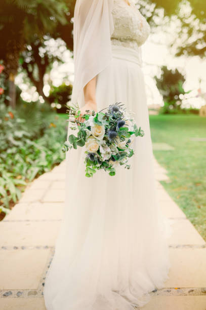 istock Crop bride with bouquet in park 1423318480