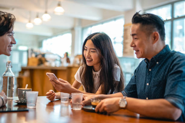 istock Chinese Friends Talking and Checking Smart Phone in Cafe 1423319196