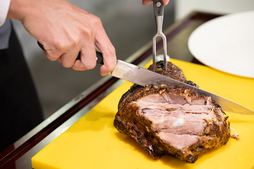 A server carving meat out from the roasted lamb leg