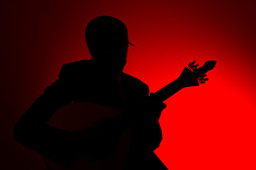 fado musician in silhouette with a portuguese guitar, studio