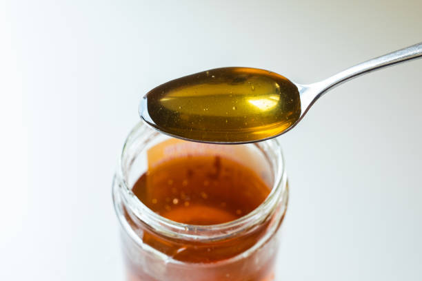 istock Smooth golden honey dropping from spoon in jar 1423321185