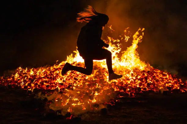 Summer solstice celebration jumping into the fire. Burning flames. Danger