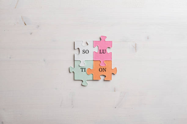 Word Solution spelled with syllables on four matching colorful puzzle pieces placed over wooden background.