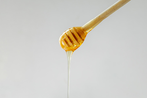 Close-up wooden scoop with pure golden honey