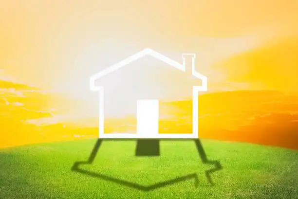 Sweet home with white color design on green grass with orange sunset background , finance, business and investment background