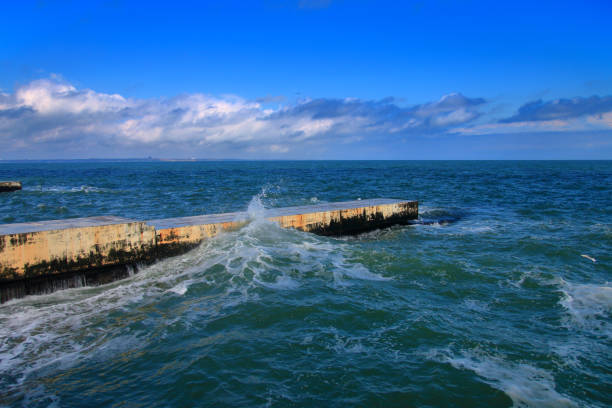 The photo was taken on the coast of the city of Odessa and Ukraine. The picture shows the sea waves of the Black Sea crashing on concrete piers into innumerable splashes.